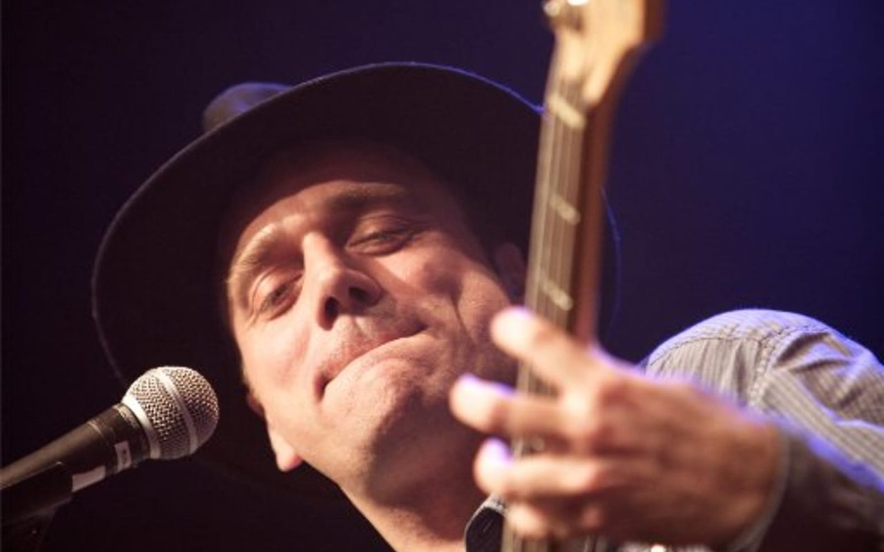Guitarist med hat synger for